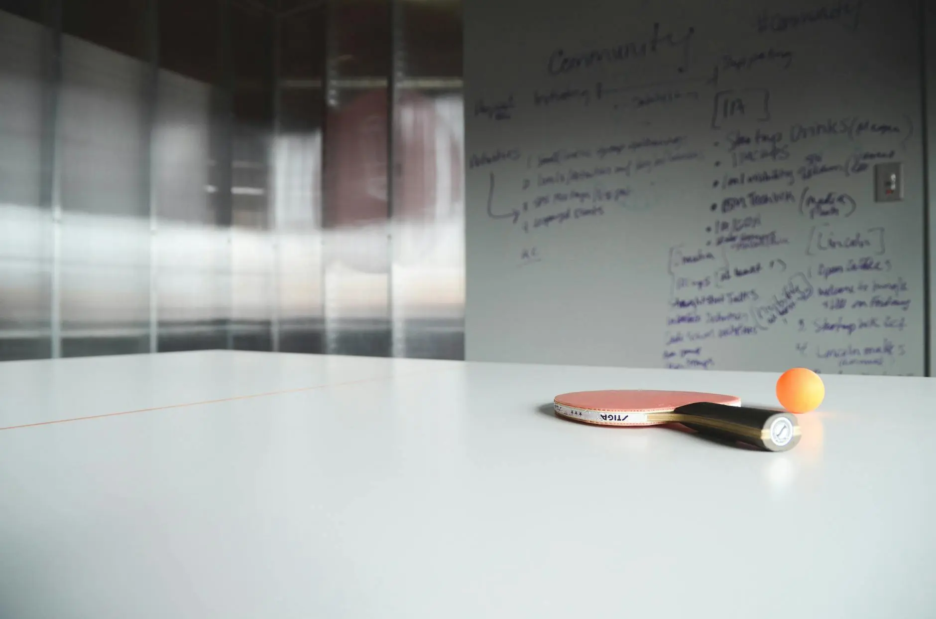 Close-up of ping pong paddle and ball on office table, creative workspace.